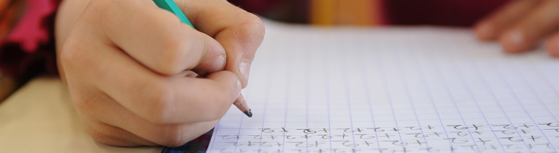 Main d'enfant écrivant sur un cahier